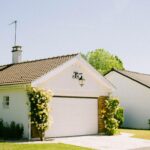 Beautiful suburban house with a garage surrounded by flowering plants in a sunny neighborhood.