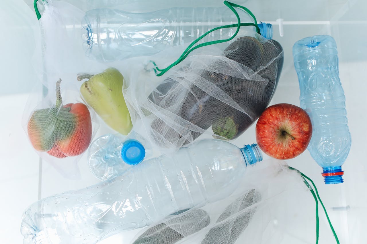 about-us Plastic bottles and vegetables in reusable mesh bags promote eco-friendly shopping.