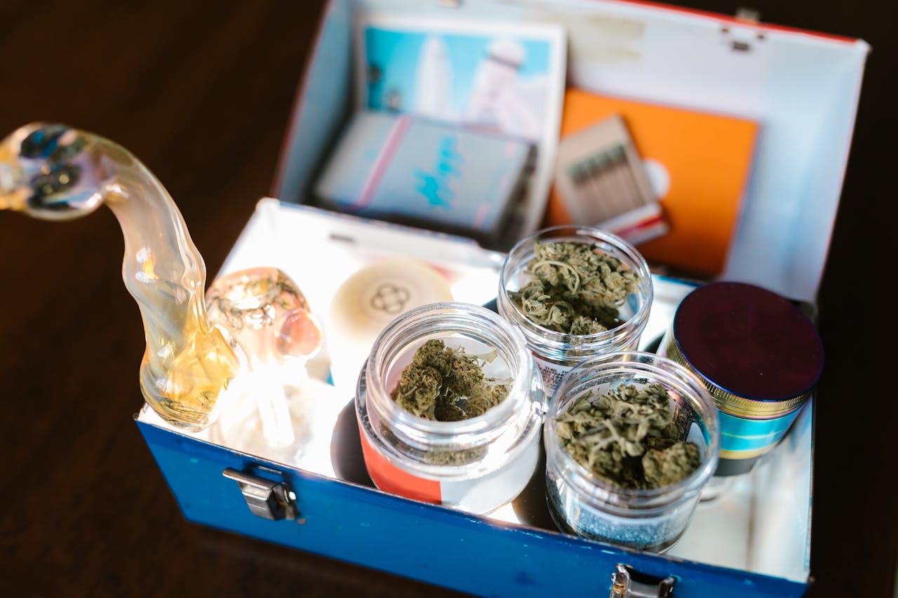 Open cannabis box containing weed, glass pipe, and rolling papers for legal use.