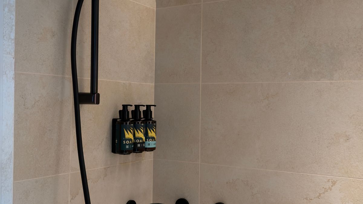 Modern minimalist walk-in shower with black fixtures and a shelf for toiletries